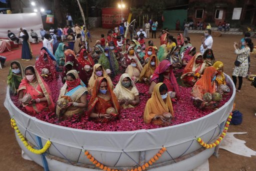 In this Nov. 20, 2020, file photo, Indian women perform rituals standing inside an artificial pond on Chhat Puja festival even as health officials warned about the potential for the coronavirus to spread during the religious festival season, in Mumbai, India.