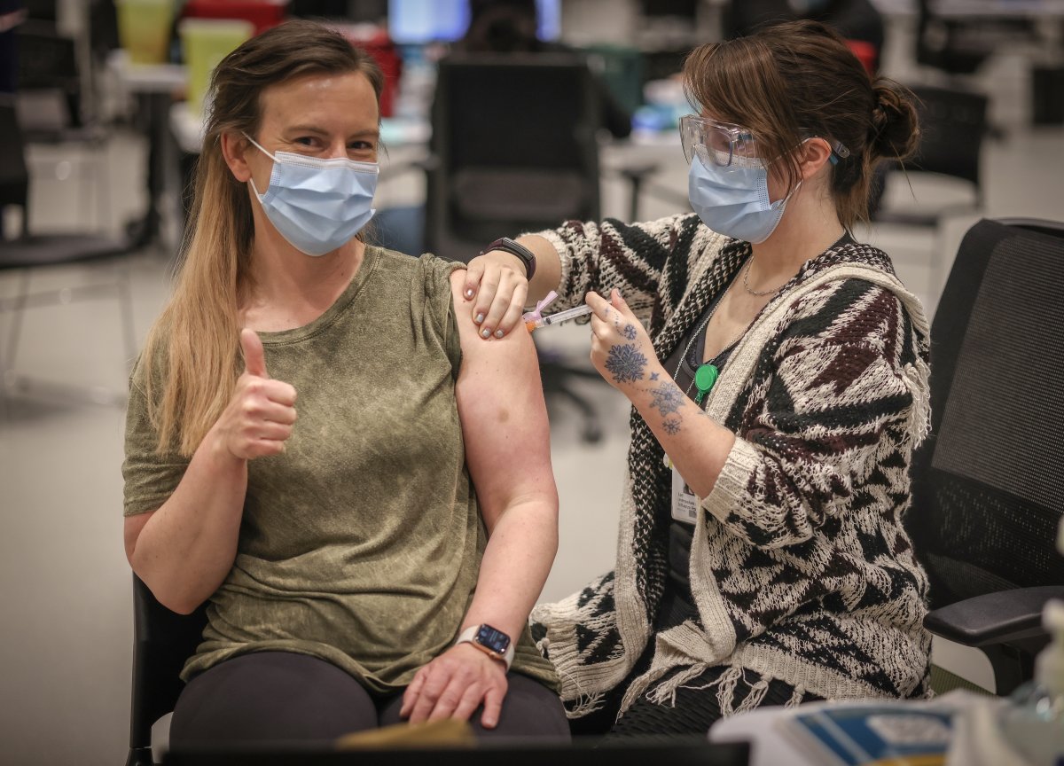 Lana Weatherdon, 43, receives the AstraZeneca vaccine from Lee Buzzell-Lavoie at the Telus Convention Centre immunization site in Calgary on April 20, 2021.