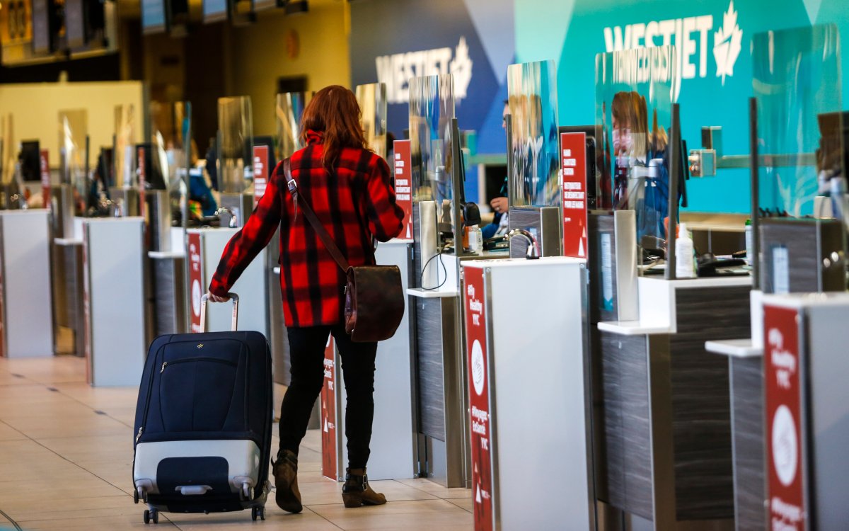 A passenger checks in at a Westjet counter at  the Calgary Airport in Calgary, Alta., Friday, Oct. 30, 2020, amid a worldwide COVID-19 pandemic.