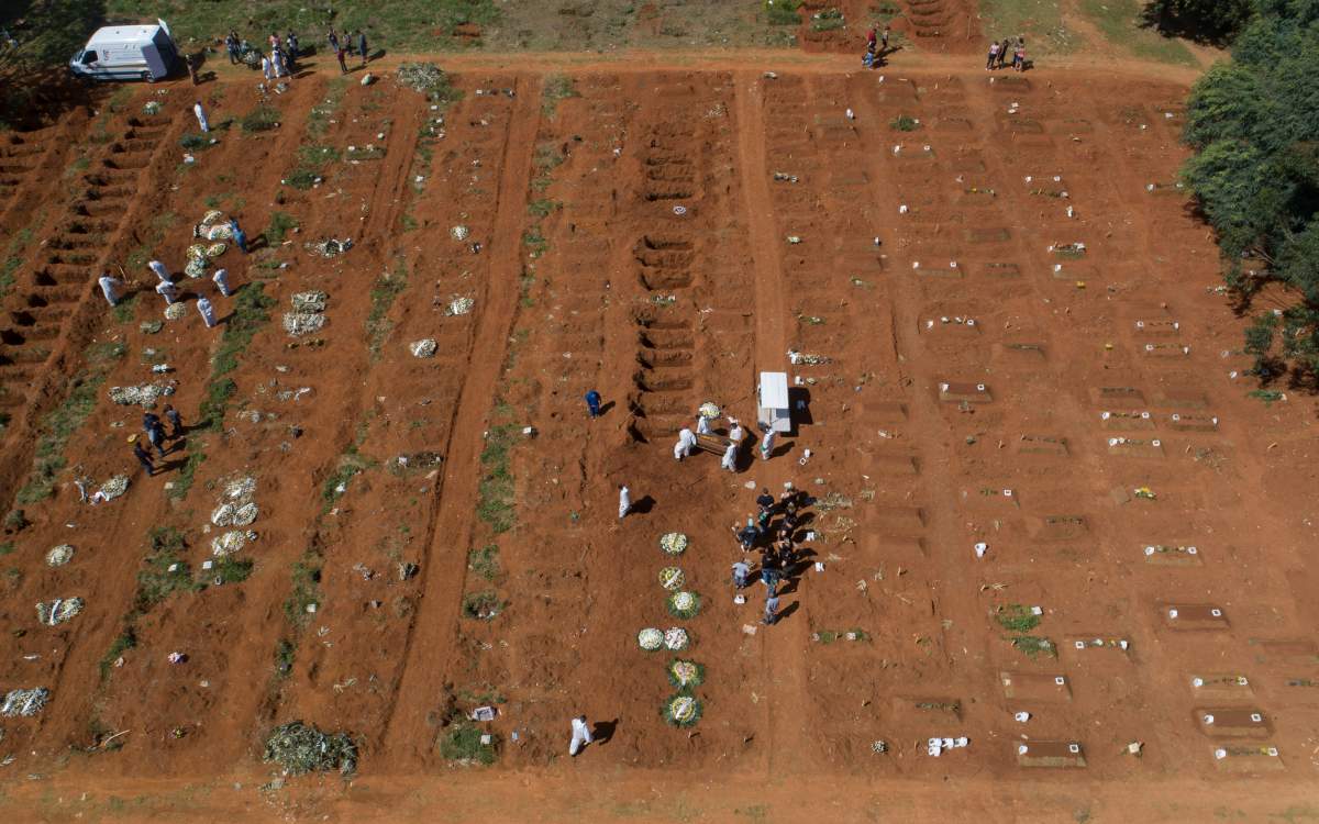 Cemetery workers in full protective gear carry a coffin that contains the remains of a person who died from complications related to COVID-19 to a gravesite at the Vila Formosa cemetery in Sao Paulo, Brazil, Wednesday, March 24, 2021. (AP Photo/Andre Penner)