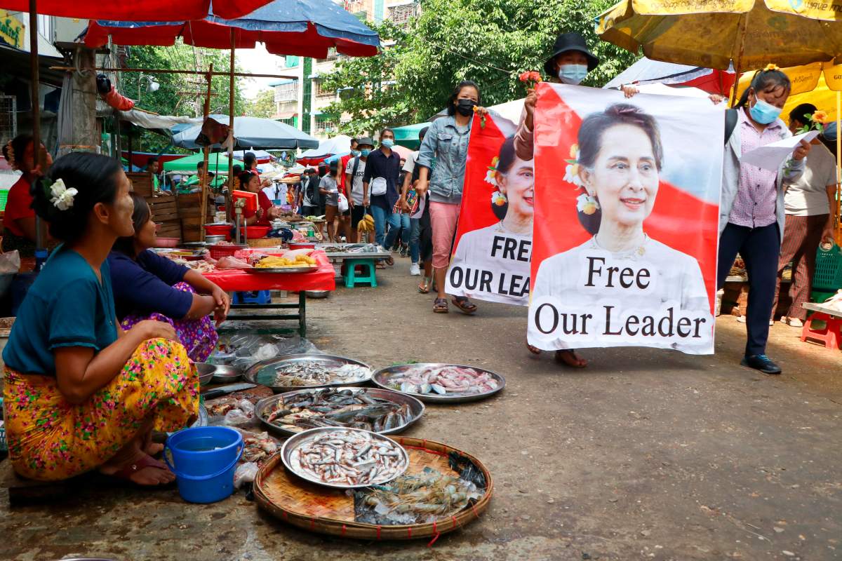 Anti-coup protesters walk through a market with images of ousted Myanmar leader Aung San Suu Kyi at Kamayut township in Yangon, Myanmar Thursday, April 8, 2021.