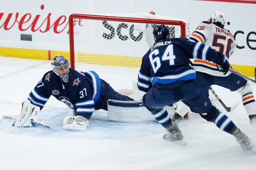 Winnipeg Jets goaltender Connor Hellebuyck (37) makes the save against Edmonton Oilers’ Kailer Yamamoto (56) as Logan Stanley (64) defends during first period NHL action in Winnipeg on Saturday, April 17, 2021.
