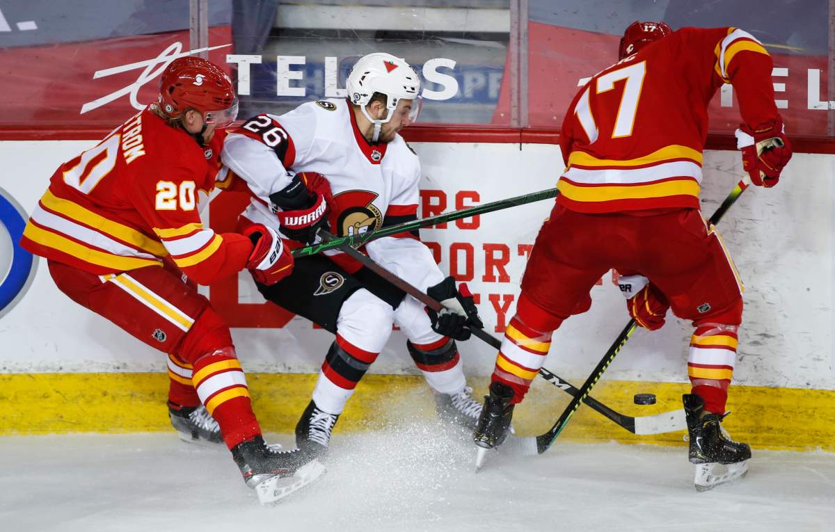 Ottawa Senators’ Erik Brannstrom, centre, tries to get the puck away from Calgary Flames’ Joakim Nordstrom, left, and Milan Lucic during third period NHL hockey action in Calgary, Alta., Monday, April 19, 2021.