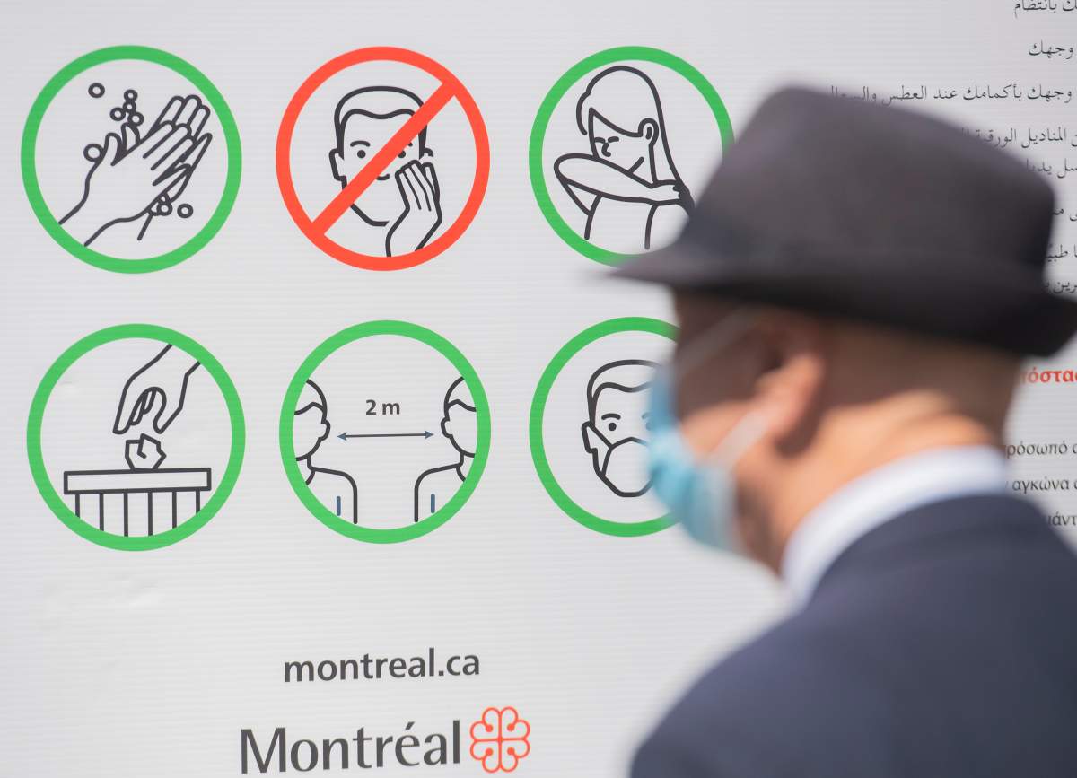 A man wears a face mask as he looks at a sign illustration COVID-19 preventative measures in Montreal, Saturday, April 24, 2021. 