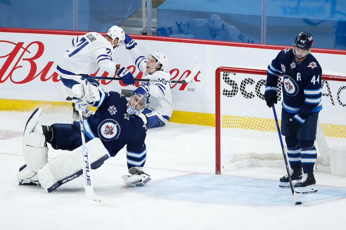 Toronto Maple Leafs' Nick Foligno (71) and Mitchell Marner (16) celebrate Marner's goal against Winnipeg Jets goaltender Connor Hellebuyck (37) during first period NHL action in Winnipeg on Saturday, April 24, 2021. 