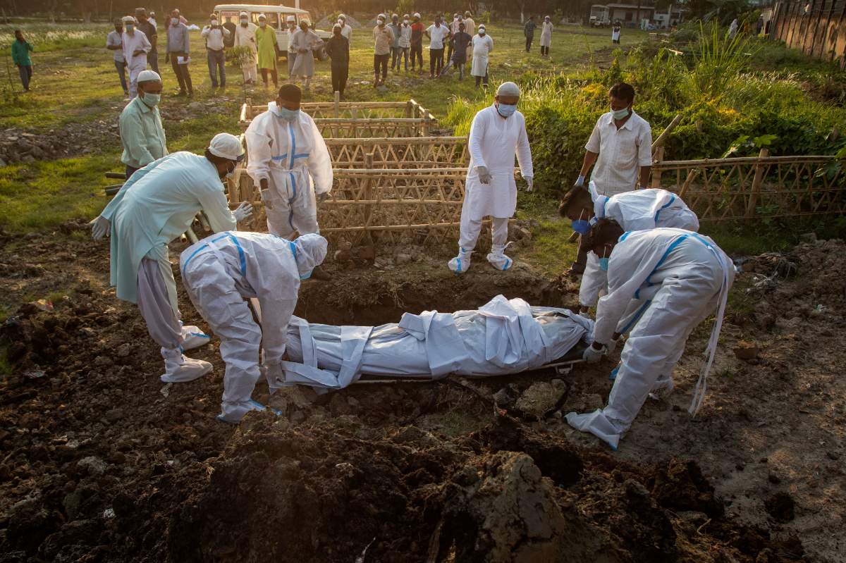 Municipal workers prepare to bury the body of a person who died of COVID-19 in Gauhati, India, April 25, 2021.