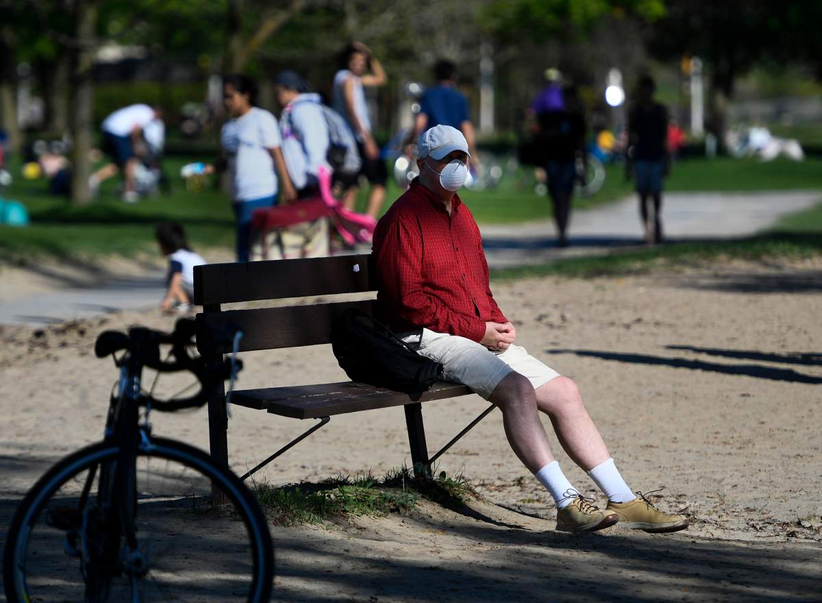 A person rests on a bench at Mooney's Bay Beach in Ottawa, on Saturday, May 23, 2020, in the midst of the COVID-19 pandemic. City staff might implement stricter closing times on the site and other parks in the city this summer.