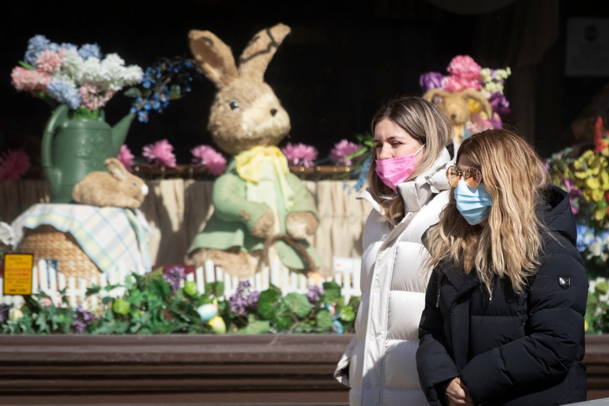 People wear masks to protect them for the COVID-19 virus while walking past a store with Easter decorations in Kingston, Ontario on Friday, March 19, 2021.