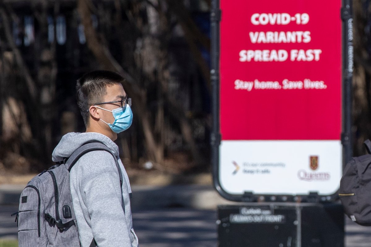 A person wears a disposable mask to protect them from the COVID-19 virus while standing beside information about the ongoing pandemic in Kingston, Ontario on Monday, April 5, 2021. THE CANADIAN PRESS IMAGES/Lars Hagberg.