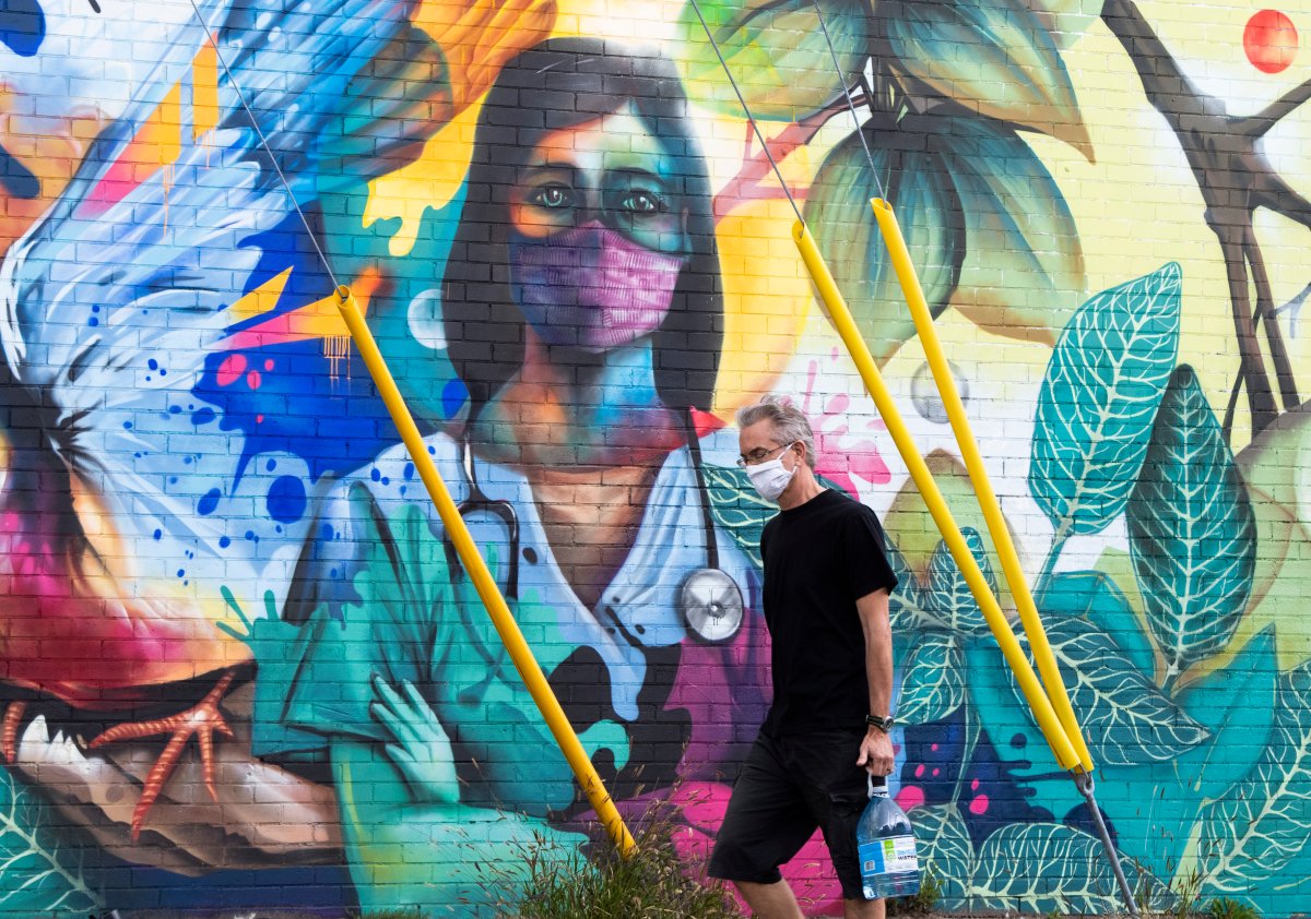 A person walks past a mural by artist Dom Laporte showing a health care worker in Ottawa.