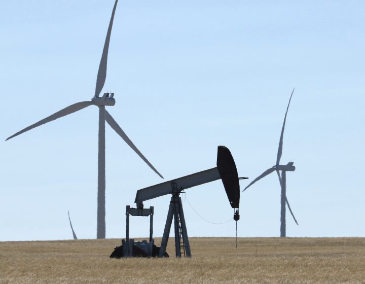 FILE: Oilfield pumpjack on an oil well, foreground, and wind energy turbines on a wind farm near Carmangay, Alberta on Sept. 10. 2020.  
