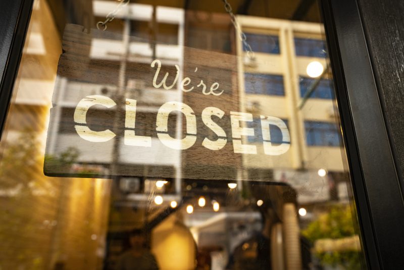 File: Closed sign hanging in business window by a string.