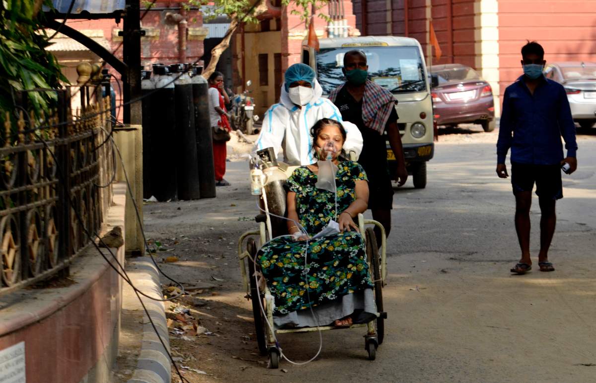 A Covid-19 patient on a wheel chair goes for a medical test inside a government hospital in Kolkata, India, 27 April, 2021.