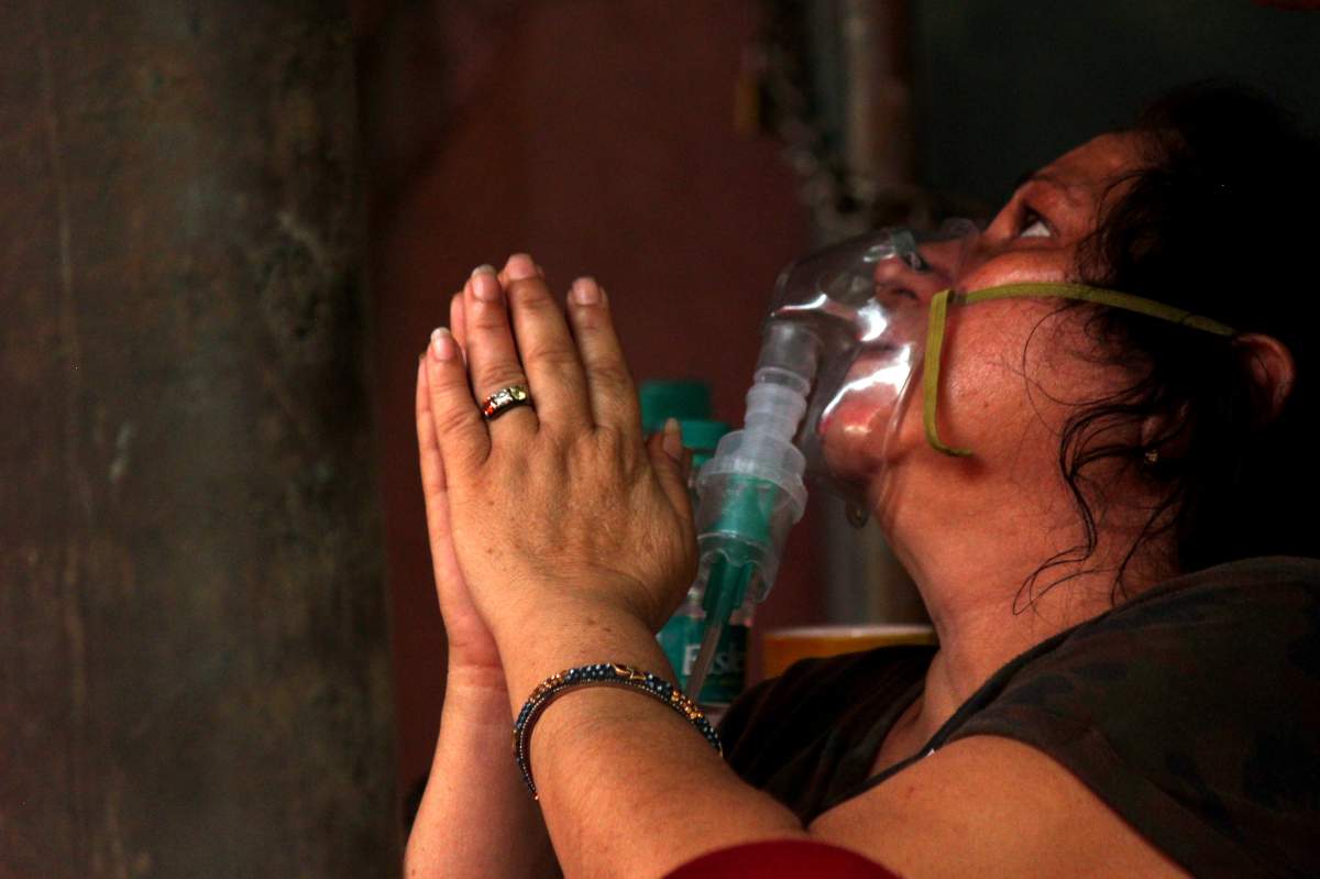 A woman suffering from a breathing difficulty due to the coronavirus disease (COVID-19), prays while receiving free oxygen support outside a Gurudwara (Sikh temple) in Ghaziabad, India, on April 28, 2021.