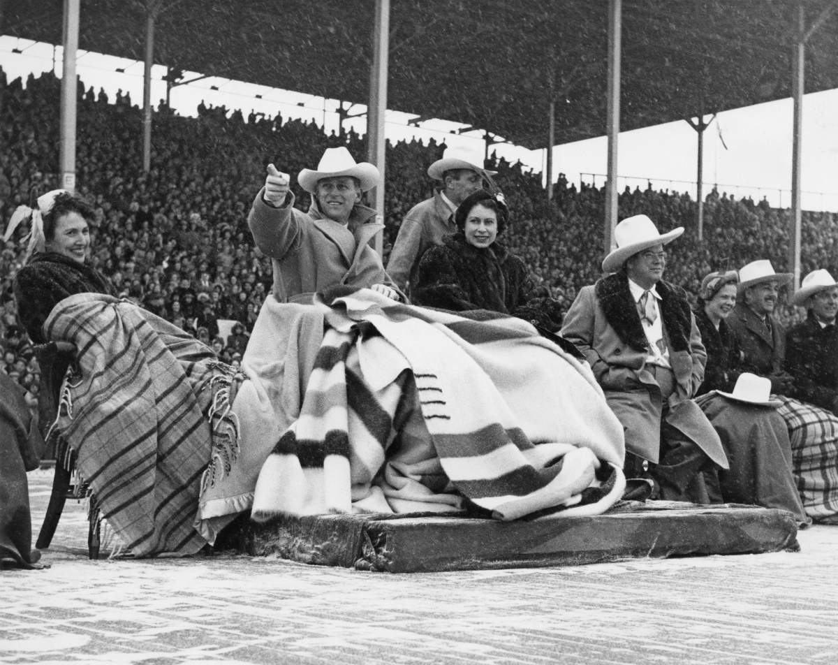 Princess Elizabeth and Prince Philip brave a snowstorm to watch a stampede at Calgary exhibition grounds, Canada, Oct. 24, 1951. Next to the Princess is Donald Hugh Mackay, Mayor of Calgary. The Princess is wearing a mink fur coat, a wedding present from Canada.