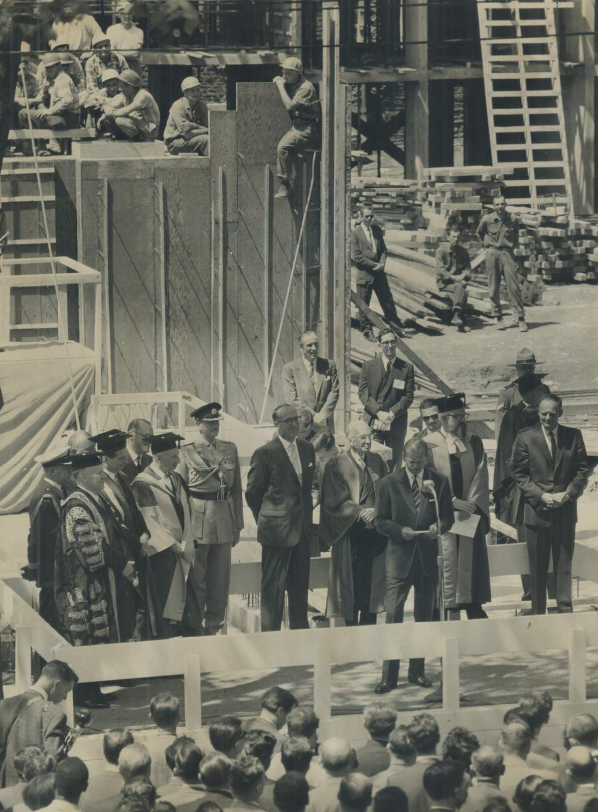 Workmen pause to listen as Prince Philip gives an address at Massey College in Toronto where he laid the foundation stone in 1962.