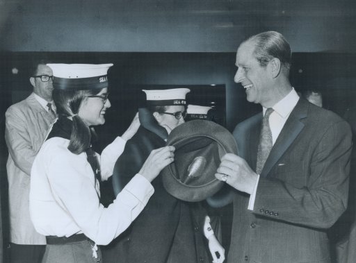 It may look like a tug-of-war; but it’s just Dianne Murray returning Prince Philip’s hat to him after a rally of Venturer Scouts in the Scarborough Centennial Arena. Philip presented certificates to teenagers who have completed requirments for the Duke of Edinburgh Award; and looked at displays of activities.