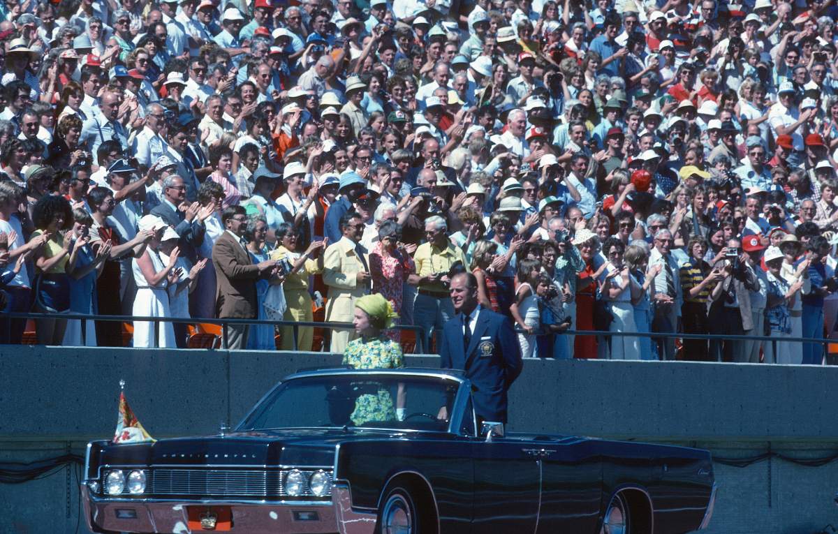 Queen Elizabeth ll and Prince Philip, Duke of Edinburgh ride in an open car past spectators in the stands as they arrive to open the Commonwealth Games on Aug. 3, 1978, in Edmonton, Canada.