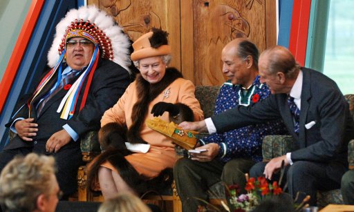 Queen Elizabeth II is shown some moccasins by the Duke of Edinburgh after he was presented with them during their visit to the First Nations University in Regina.