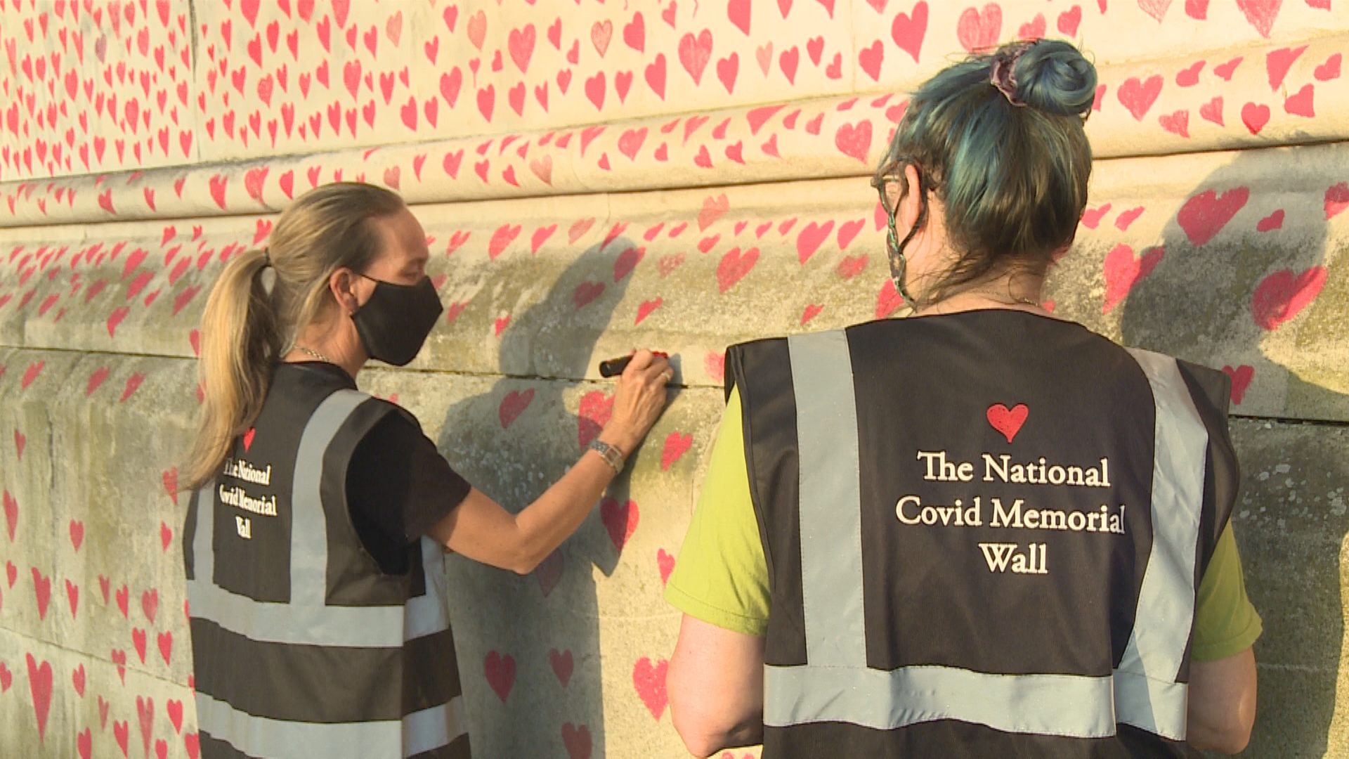 Sophie Rawlings (left) and another member of Covid-19 Bereaved Families for Justice UK paints hearts on the National Covid Memorial Wall in London, England.