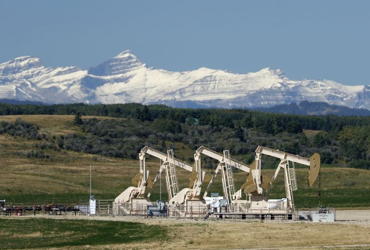 Oilfield pumpjacks, belonging to Whitecap Resources, work producing crude near Calgary, Alberta on Sept. 9, 2020. The Rocky Mountains are visible in the distance. 