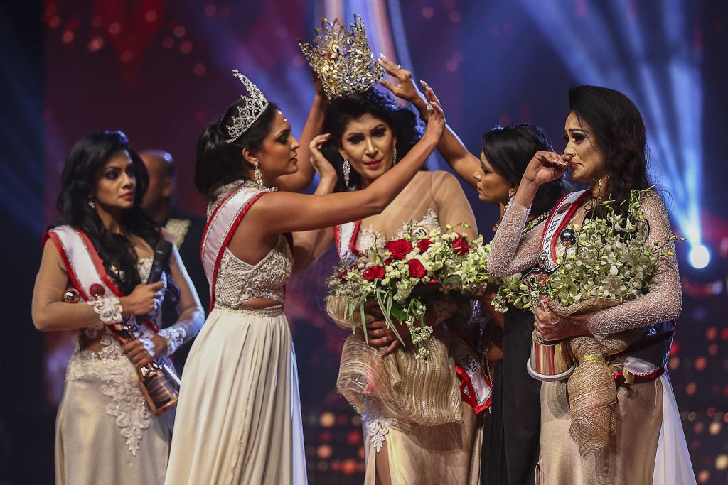 In this photograph taken on April 4, 2021, winner of Mrs. Sri Lanka 2020 Caroline Jurie (2-L) removes the crown of 2021 winner Pushpika de Silva (C) as she is disqualified by the jurie over the accusation of being divorced, at a beauty pageant for married women in Colombo.