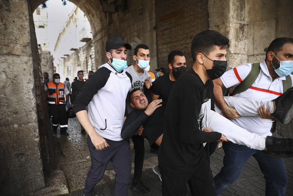 Palestinians evacuate a wounded protester during clashes with Israeli security forces at the Lions Gate in Jerusalem’s Old City, Monday, May 10, 2021.