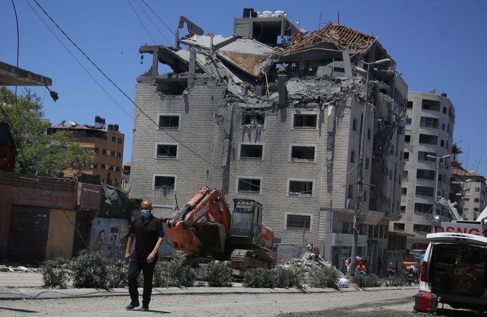 A Palestinian walks by a building hit by an Israeli airstrike in Gaza City, Tuesday, May 18, 2021.