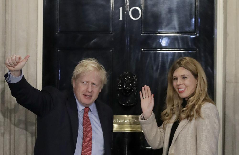 In this Friday, Dec. 13, 2019, file photo, Britain's Prime Minister Boris Johnson and his partner Carrie Symonds wave from the steps of number 10 Downing Street in London. U.K. newspapers are reporting that Prime Minister Johnson and his fiancée Symonds married Saturday, May 29, 2021, in a small private ceremony in London. The Mail on Sunday and the Sun said the couple wed at the Roman Catholic Westminster Cathedral in front of a small group of friends and family.