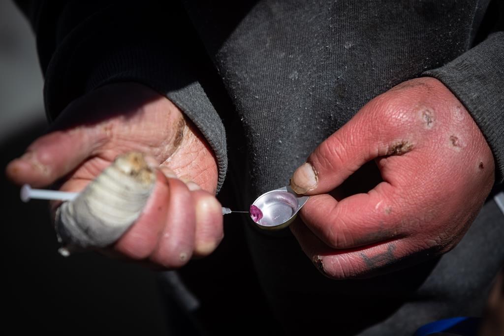 A man draws an unknown illicit substance into a syringe before injecting it into his arm during a rally and march to mark the five-year anniversary of British Columbia declaring a public health emergency in the overdose crisis, in Vancouver, on Wednesday, April 14, 2021.