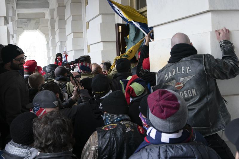 FILE - In this Jan. 6, 2021 file photo insurrectionists loyal to President Donald Trump try to open a door of the U.S. Capitol as they riot in Washington. With riot cases flooding into Washington’s federal court, the Justice Department is under pressure to quickly resolve the least serious cases. 