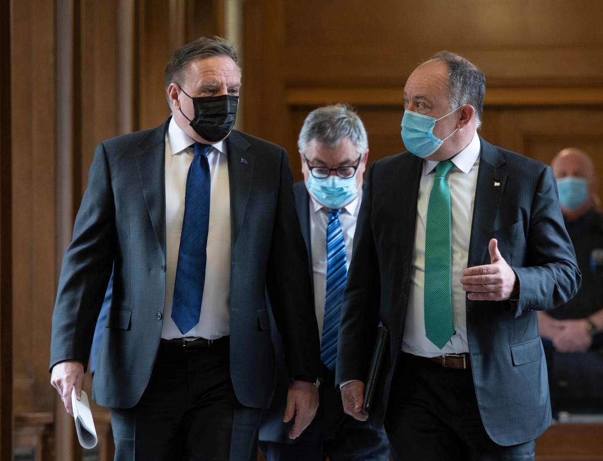 Quebec Premier Francois Legault, left, chats with Quebec Health Minister Christian Dube, right, as they walk to a news conference on the COVID-19 pandemic, Tuesday, May 4, 2021 at the legislature in Quebec City. Horacio Arruda, Quebec director of National Public Health follows. 