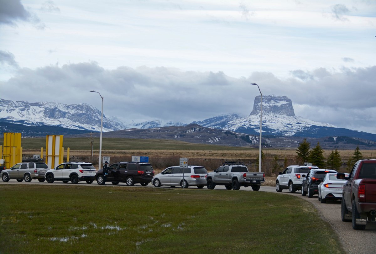 In this Thursday, April 29, 2021, photo, Canadians drive-in at the Piegan-Carway border to receive a COVID-19 from the Blackfeet tribe near Babb, Mont. The Chief Mountain, sacred to the Blackfeet tribe towers, are seen in the background. The Blackfeet tribe gave out surplus vaccines to its First Nations relatives and others from across the border. 