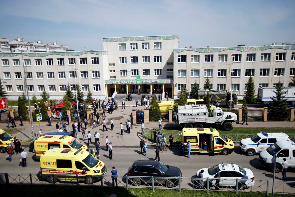 Ambulances and police cars and a truck are parked at a school after a shooting in Kazan, Russia, Tuesday, May 11, 2021.