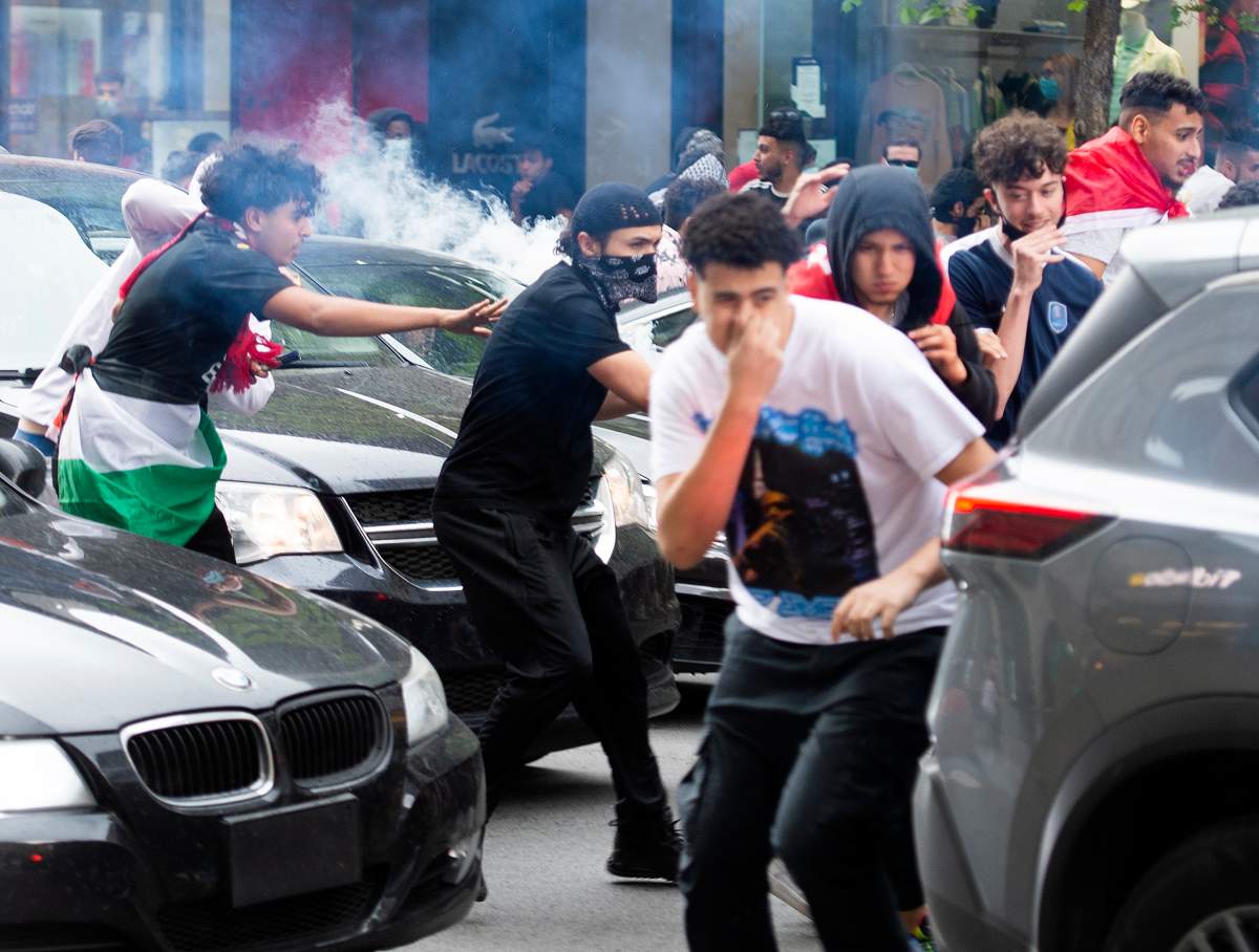 Pro-Palestinian supporters cover their faces as a chemical irritant is deployed by police following a demonstration in Montreal, Sunday, May 16, 2021. 