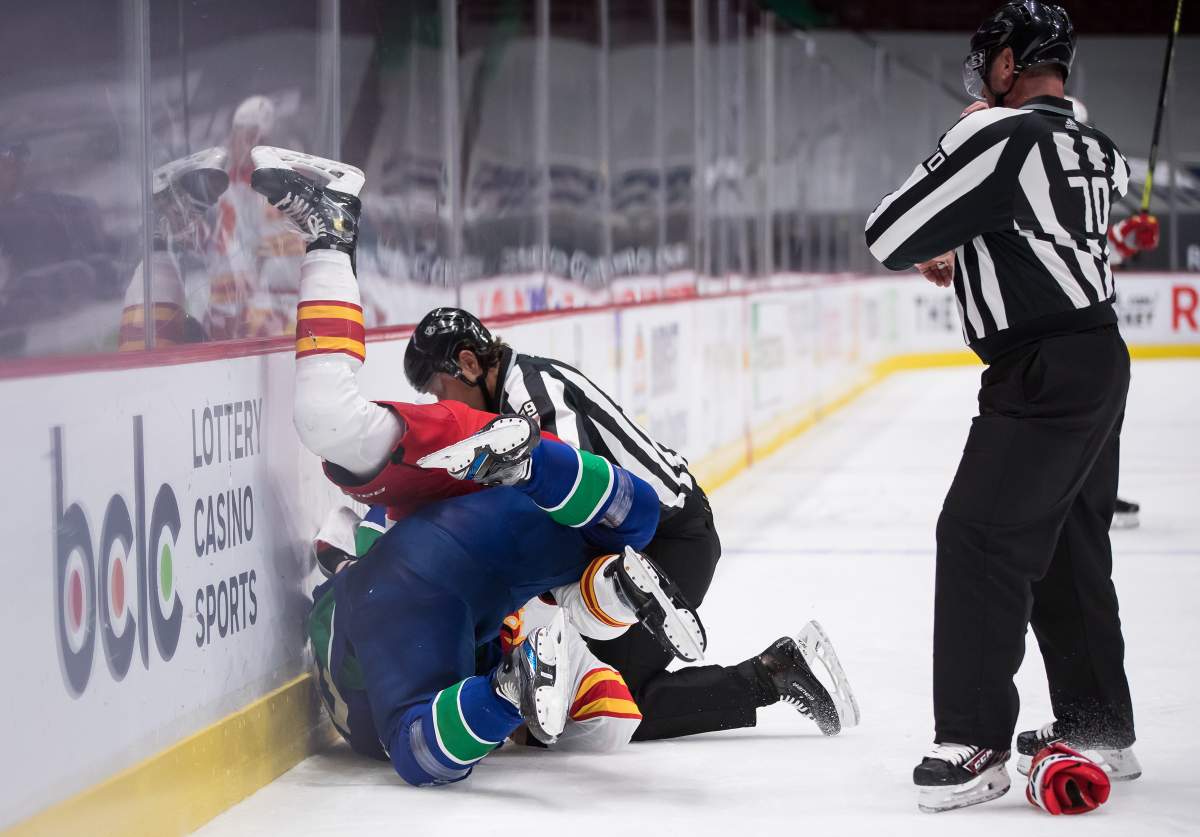 Vancouver Canucks’ Bo Horvat, front left, and Calgary Flames’ Connor Mackey fall to the ice as they fight during second period NHL hockey action in Vancouver on Tuesday, May 18, 2021.