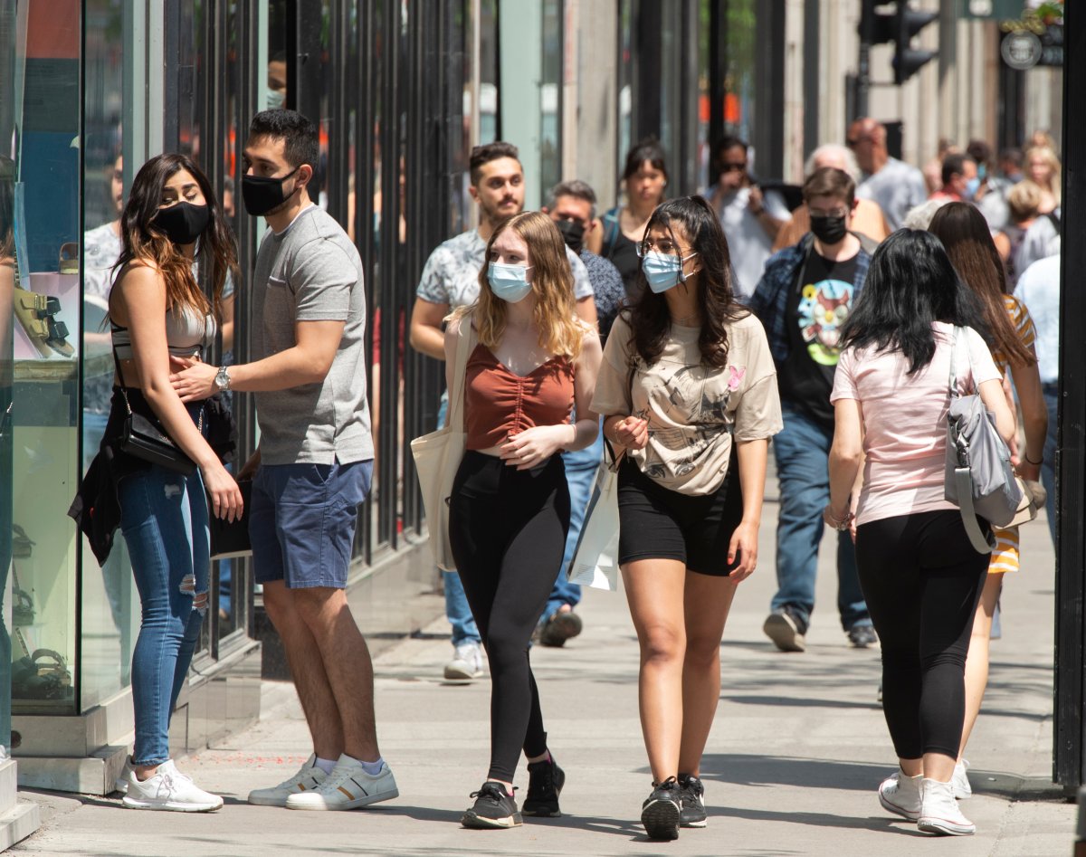 People enjoy the warm weather as they walk along St. Catherine street Wednesday, May 19, 2021  in Montreal. The provincial government has announced that COVID-19 restrictions will begin easing in the coming weeks. 