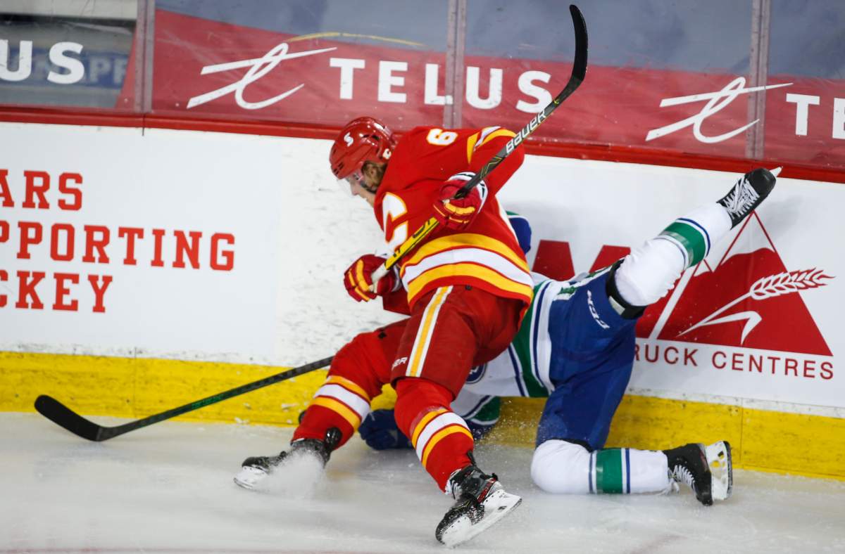Vancouver Canucks’ Kole Lind, right, is checked by Calgary Flames’ Juuso Valimaki during second period NHL hockey action in Calgary, Wednesday, May 19, 2021.
