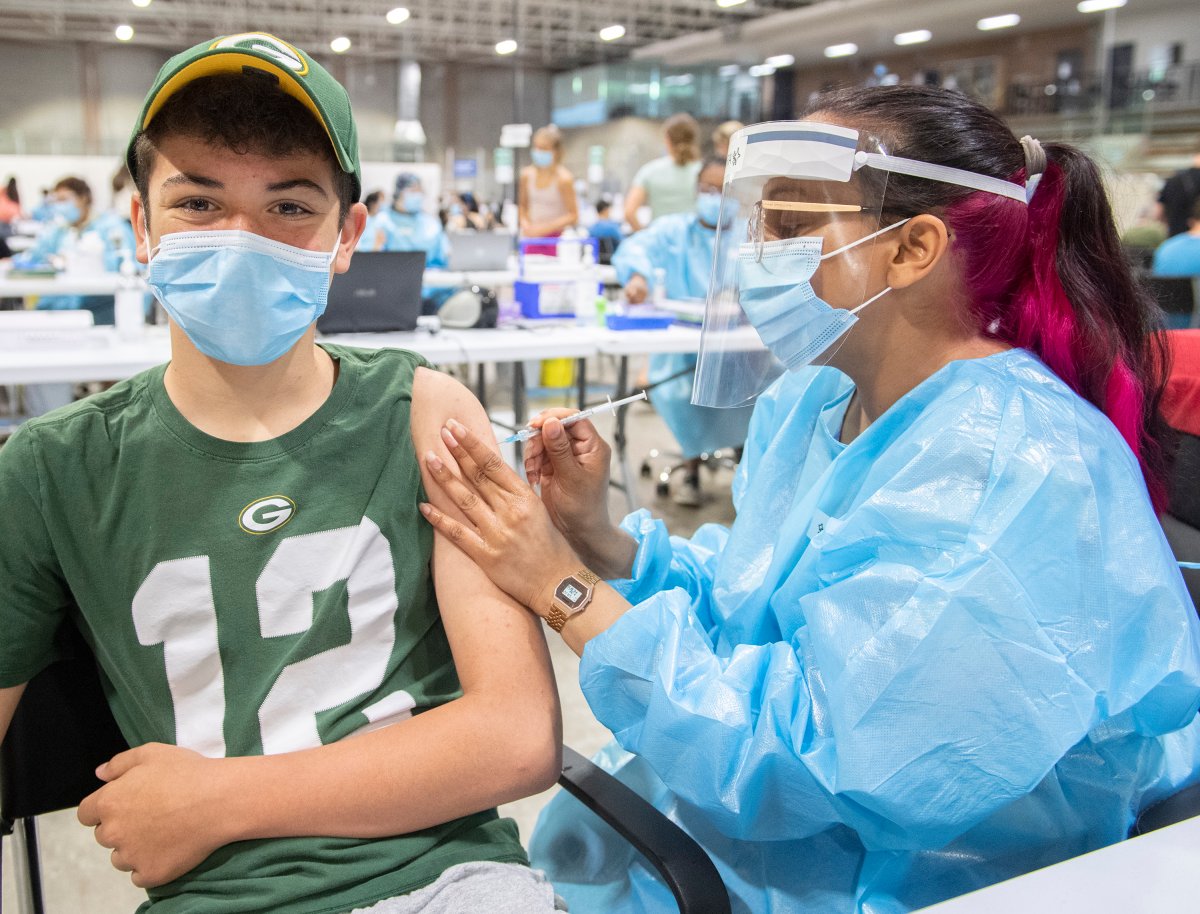 JJ Fixman, 14, receives a COVID-19 vaccine shot from Stara Sinanan at a COVID-19 vaccination site in Montreal, Saturday, May 22, 2021. 