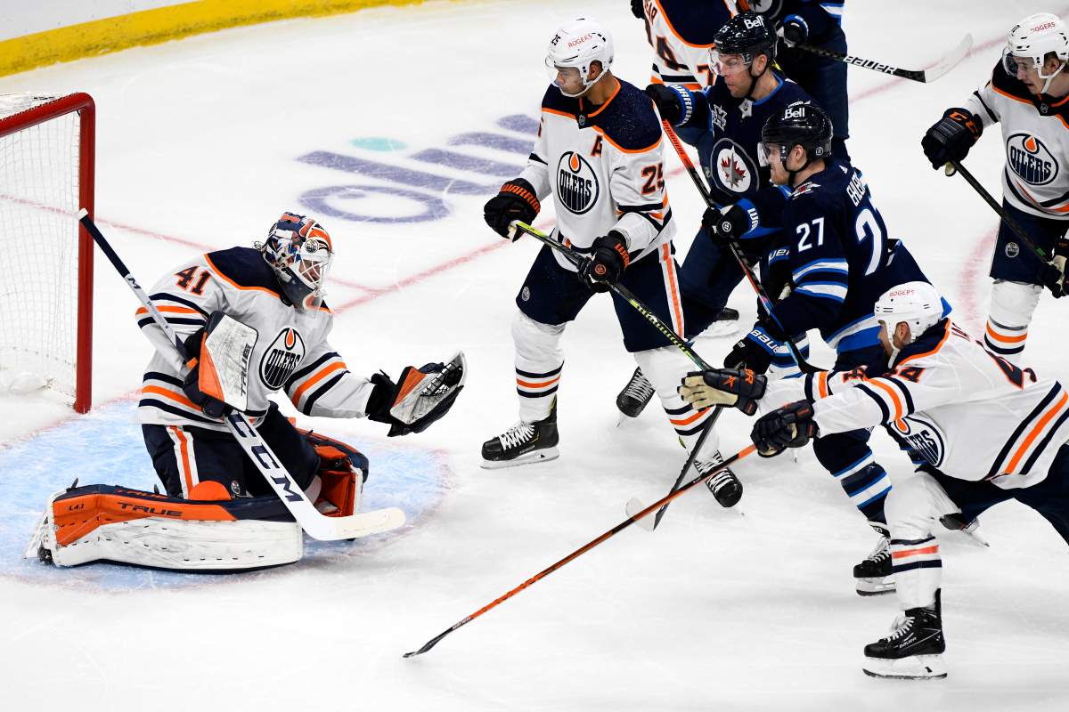 Edmonton Oilers goaltender Mike Smith (41) makes a save on a Winnipeg Jets shot as players look for the rebound during first period NHL action in Winnipeg on Sunday, May 23, 2021.