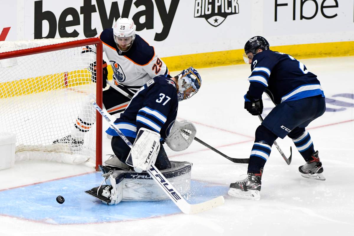 Edmonton Oilers’ Leon Draisaitl (29) shoots the puck through the crease by Winnipeg Jets goaltender Connor Hellebuyck (37) during first overtime period NHL Stanley Cup playoff action in Winnipeg on Monday, May 24, 2021.