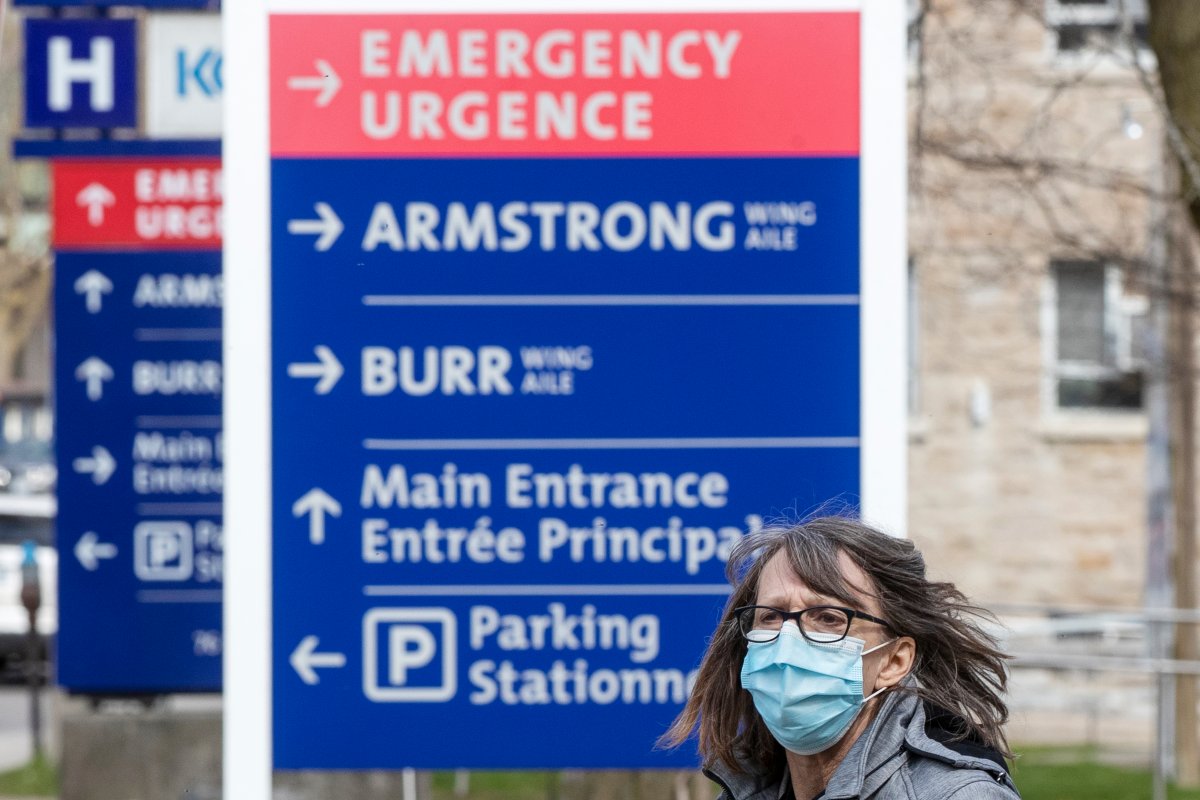 A person wears a surgical mask to curb the spread of the COVID-19 virus while walking by signage outside Kingston General Hospital in Kingston, Ont., on Tuesday April 27, 2021, as the COVID-19 pandemic continues across Canada and around the world.