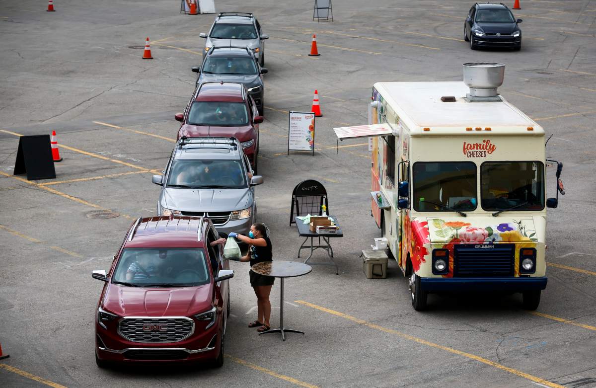 A server delivers food to a vehicle during a drive-thru food truck rally as people try to enjoy the Calgary Stampede even though it was cancelled due to the COVID-19 pandemic on Saturday, July 4, 2020.