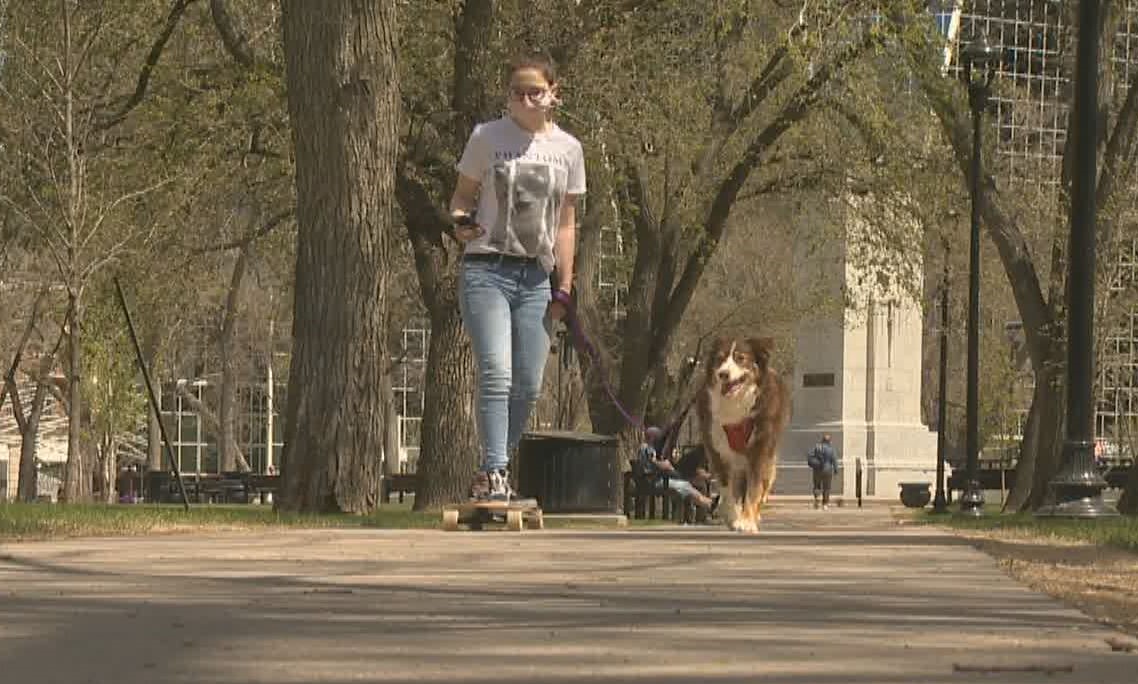 Easy Breezy Bike Challenge organizer Sydney Chadwick, with her dog by her side, skateboards through Victoria Park in Regina on Friday. 