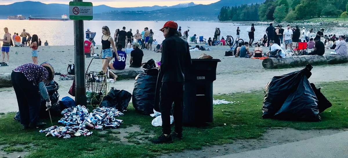Binners are cleaning up empties at English Bay in Vancouver Sunday after a large crowd of people gathered on the beach to drink and party.