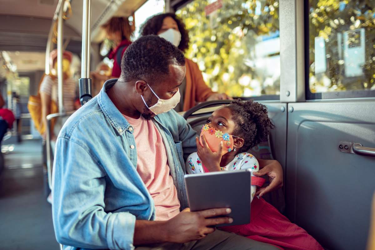 A father and daughter wearing masks on a bus.
