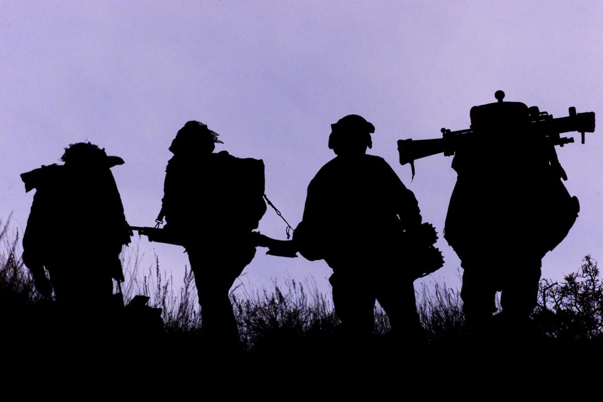FILE - Canadian infantry soldiers from 3-PPCLI carry battle gear including a shoulder launched rocket as they walk a ridge line March 14, 2002 in the Shahi Kot mountains in Afghanistan.