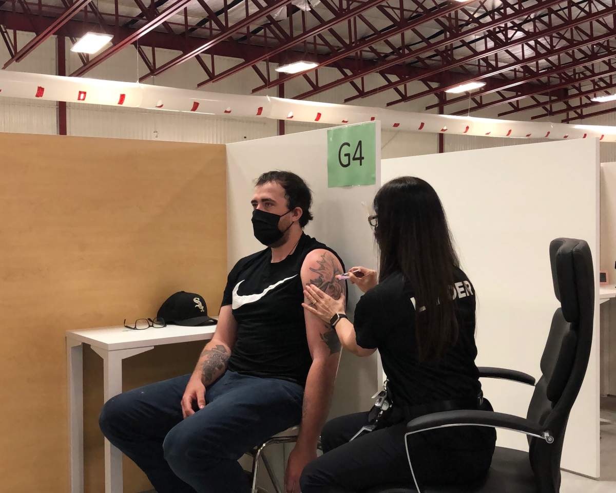 Ryan Gosso, a 25-year-old grocery store worker receives a COVID-19 vaccine from registered nurse Melissa Thompson as he becomes the first person to receive a shot from the new clinic at Earl Nichols Recreation Centre.