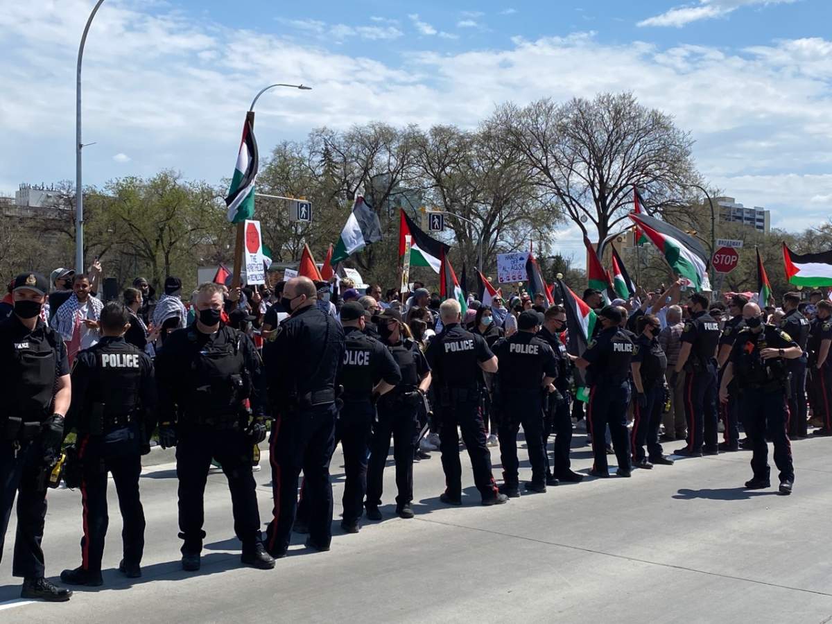 A line of Winnipeg police officers stand in between groups of pro-Israel and pro-Palestinian demonstrators Saturday afternoon.