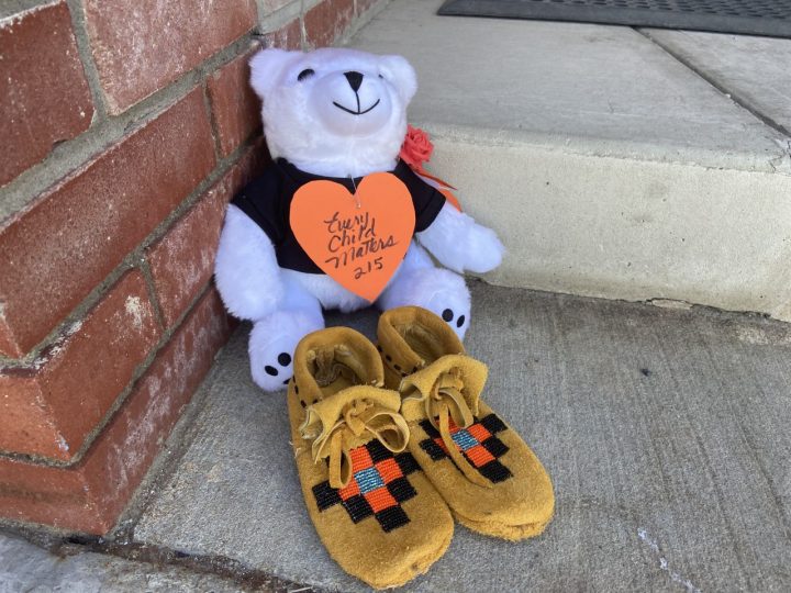 A bear and pair of moccasins sit on the steps of the former Old Sun residential school near Gleichen, Alta., pictured on May 31, 2021.